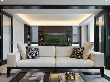 Modernes Sofa in schwarzweissem Ambiente mit Aquariumwand im Hintergrund