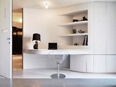 See-through shell chair in front of white multi-purpose furniture -- room partition with work surface and shelves