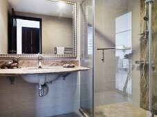 Vanity with stone tiles in front a a mirror next to a glass shower stall