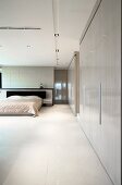 Minimalist bedroom with built-in cupboards and illuminated, suspended ceiling panels