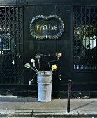 Collection of vintage, metal table lamps in bin in front of old shop with closed window grilles