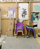 Colourful plastic nesting chairs and wooden storage boxes in front of DIY partition wall