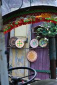 View through vehicle windscreen of round chopping boards painted with colourful patterns leaning on purple painted wooden door