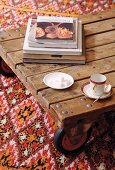 Mocha cup and saucer and sugar cubes on low wooden table with castors on patterned rug