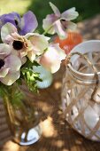 Flowers in bottle and tealight holder on wicker table mat