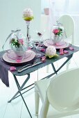 White plastic chairs around vintage folding table with place settings and decorations