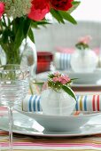Place setting with flower arrangement and linen napkin with multicoloured stripes