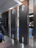 Designer bedroom with black sliding doors and integrated LED strip lighting in front of an en suite bathroom