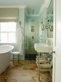 Blick durch offene Tür auf Waschtisch und freistehende Vintage Badewanne am Fenster auf Bodenfliesen mit Wabenmuster
