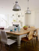 Rustic kitchen table and modern chairs below industrial lamps in country-style interior