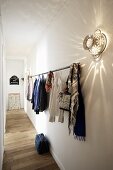 Clothes rod and vintage wall light made from an aluminum colander on a long hallway