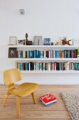 Low, wooden Bauhaus chair in front of white floating bookshelves