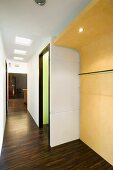 Dark wood flooring in a hallway with a curved, yellow wardrobe wall