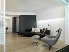 Designersofa und -Sessel in modernem Wohnzimmer mit abgehängter Decke und indirekter Beleuchtung
