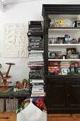 A stack of books next to a black cabinet filled with lots of things