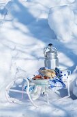 Würstchen, Brot und Thermoskanne auf einem Schlitten im Schnee