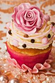 A cupcake decorated with a pink sugar rose and buttercream