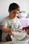 Kleiner Junge siebt Mehl in eine Schüssel