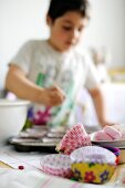 Young boy pouring cupcake mix into moulds