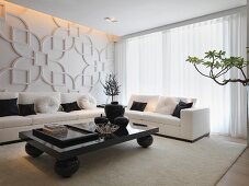 Moderner Bodencouchtisch auf kugelförmigen Füssen vor heller Couchgarnitur und gestaltete Wand mit Blumenmotiven