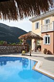 Hanging chair and parasol next to swimming pool on terrace (Villa Octavius, Lefkas, Greece)