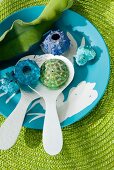 Plastic seashells on salad servers in bowl and green raffia place mat