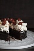 Chocolate cake topped with cream cheese and cherries