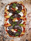 A pizza topped with black pudding, mozzarella and coriander