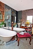 Twin freestanding bathtubs with standpipe tap fittings and various antique furnishings in crammed lounge-style bathroom