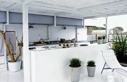A white open plan kitchen on a covered terrace