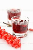 Glasses of redcurrant jelly and fresh redcurrants