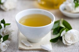 A tea bowl of green tea, surrounded by gardenia flowers