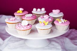 Cupcakes mit rosa und weisser Glasur und Zuckerrosen auf einer Tortenplatte