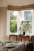 Gedeckter Tisch und Laternensammlung im Esszimmer mit Erkerfenster