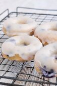 Blueberry doughnuts with icing sugar on a wire rack