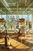 Lounge in conservatory with guitar and white upholstered chairs around glass table