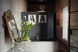 Concrete bath lined with small black ceramic tiles and partition wall in Moroccan home