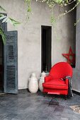 Red armchair with matching urns in courtyard of Moroccan riad in Marrakesh