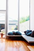 Minimalist corner bench next to terrace window with view of urban garden