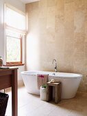 Warm shades of stone in bright bathroom with free-standing bathtub