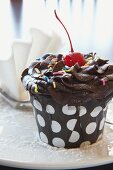 A chocolate cupcake with a cocktail cherry