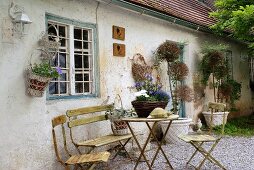 Rustic garden table and chairs on gravel floor in front of bungalow