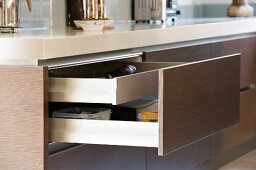 Open drawer with brown front integrated into kitchen island