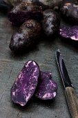 Vitelotte-Kartoffeln auf Holzbrett mit Messer