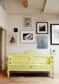 Yellow, vintage wooden bench against wall with gallery of contemporary art