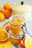 Orangenmarmelade in Einmachgläsern und frische Orangen