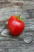 A tomato on a wooden surface