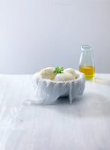 Mozzarella and olive oil in bowl lined with a muslin cloth