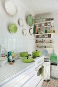 Sunny kitchen with retro cooker and collection of white and green china plates on wall