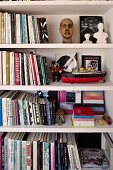 White bookshelves with small busts and a model of a ship